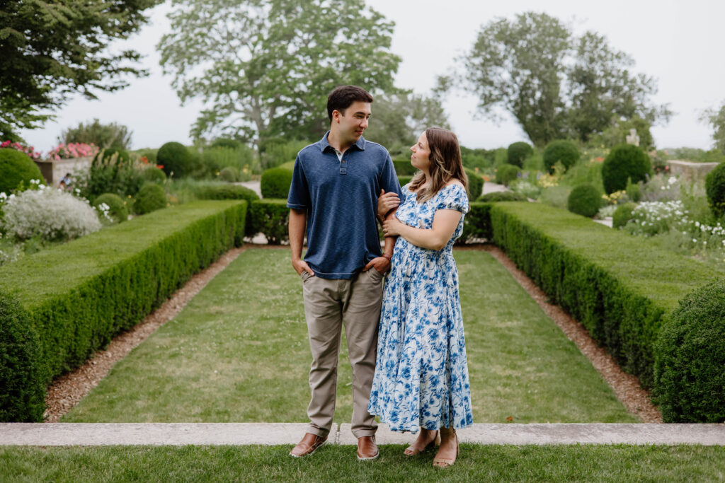 Engaged couple looking and smiling at each other in the garden at Harkness Memorial State Park in Waterford, Connecticut