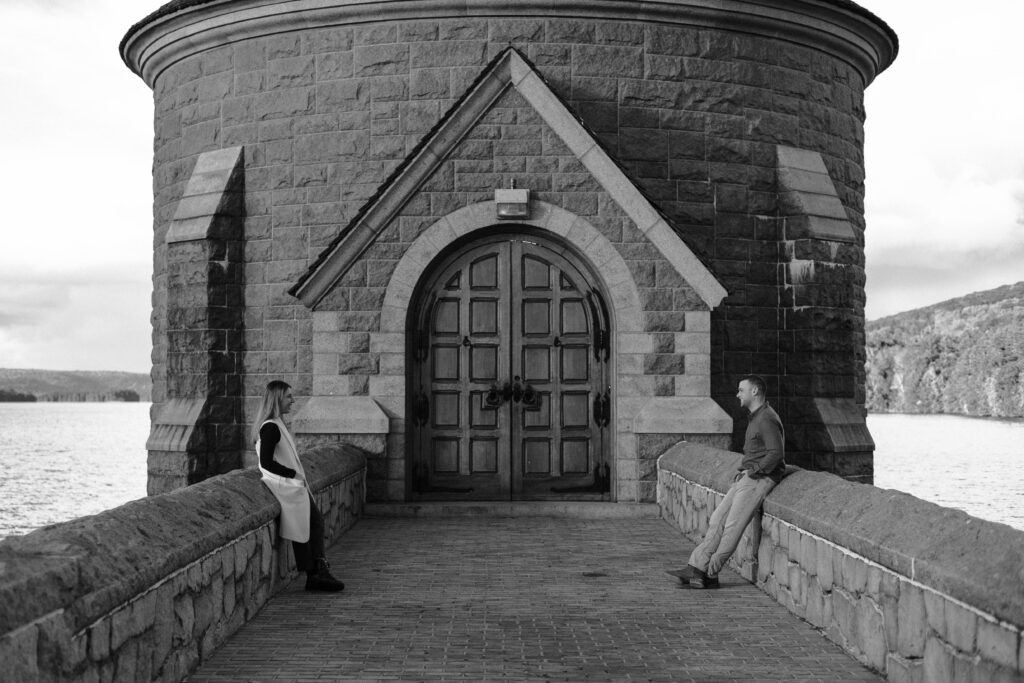 Engaged couple sitting across from each other at the Saville Dam in Barkhamsted, Connecticut