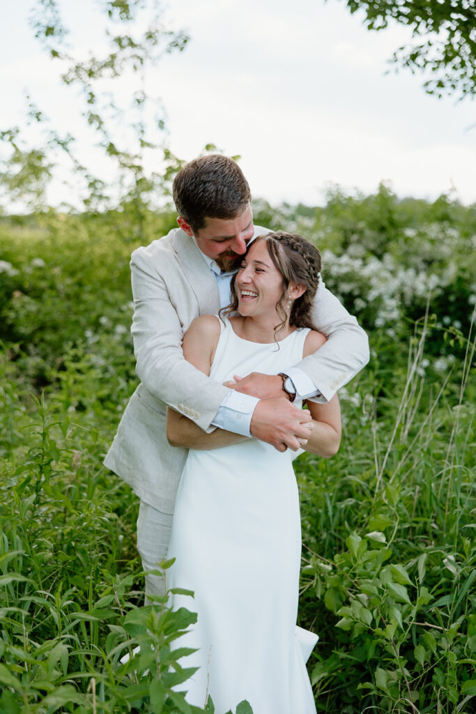 Bride and Groom embracing and smiling on their wedding day for golden hour portraits in Tolland, CT