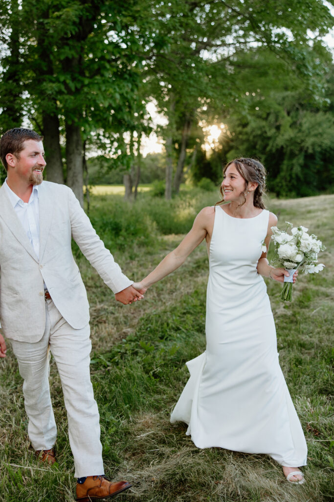 Bride and Groom smiling and walking towards the camera on their wedding day for golden hour portraits in Tolland, CT