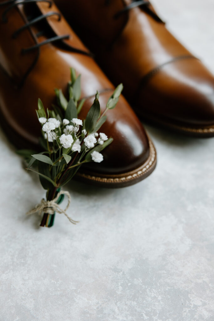 wedding day details photo of the groom's shoes and boutonniere