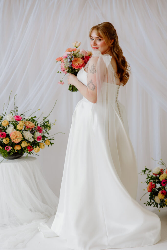 portraits of a bride with a white tulle draping backdrop and colorful spring florals