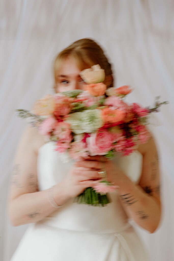 studio portrait of a bride holding colorful florals in front of her