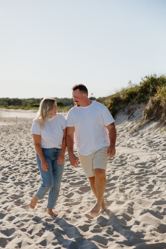 Engaged couple walking on the beach at Harkness Memorial State Park