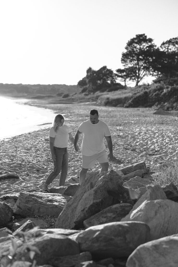 Engaged couple walking on the beach at Harkness Memorial State Park