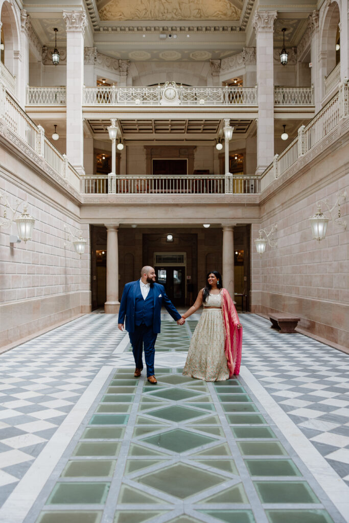 And engaged couple walking toward the camera at Hartford City Hall