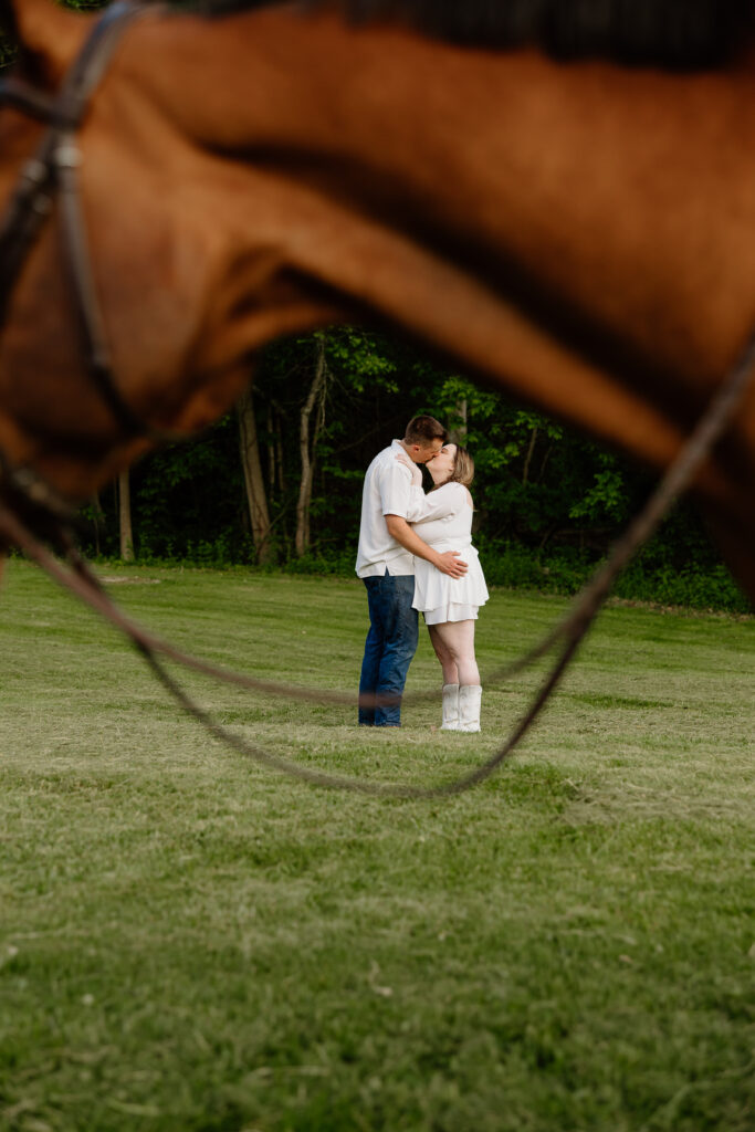 Engaged couple kissing at their horse farm