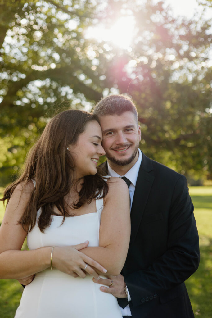 Engaged couple embracing during golden hour at Waveny Park