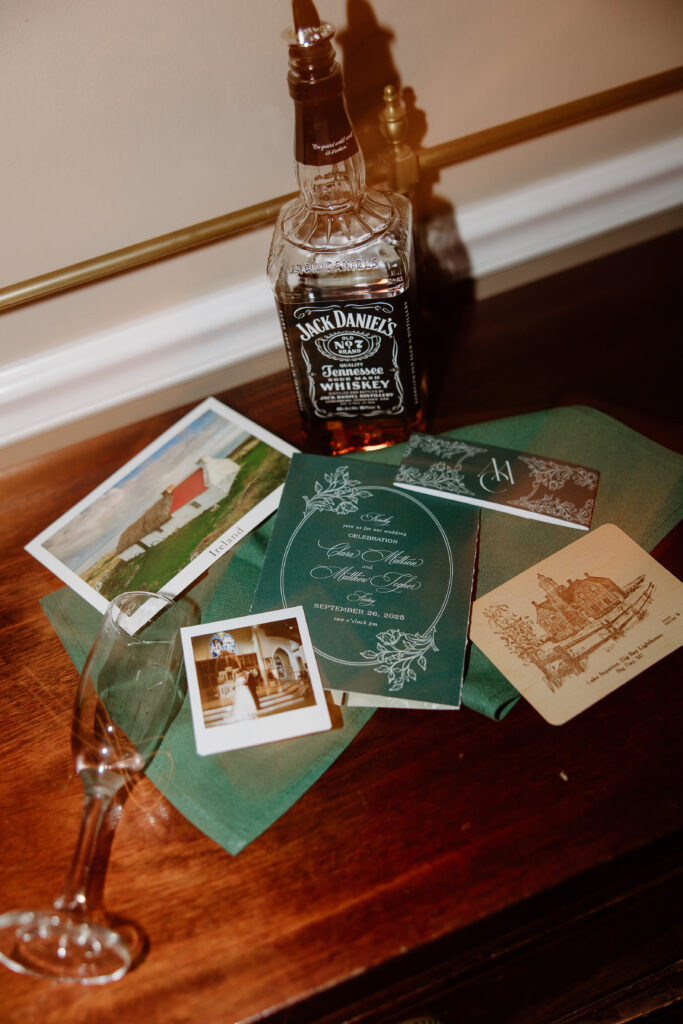 Wedding stationery and personal details displayed with a bottle of whiskey and handwritten notes, showcasing meaningful touches from Clara and Matt’s wedding day.