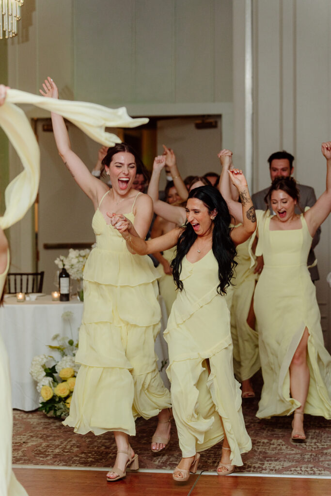 Bridesmaids waving their arms above their heads as they enter the reception