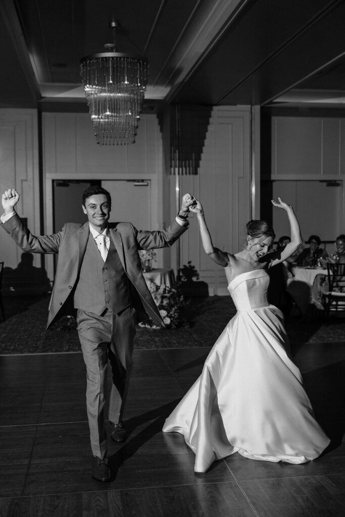 Black and white photo of the bride and groom dancing into their reception